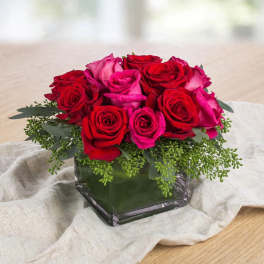 Red and pink roses arranged in a square glass vase