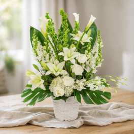 White lilies and roses arranged in a white woven basket