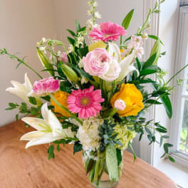 Mixed bouquet in a clear glass vase with pink, yellow, and white flowers