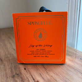 Orange Spongellé body wash buffer box on a wooden table