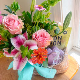 Pink roses and lilies in a gift basket with candy and soap