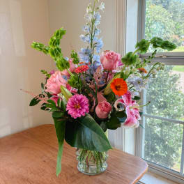 Mixed bouquet in a clear glass vase with pink, blue, and orange blooms