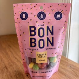 Pink bag of sour cocktail gummies standing on a wooden table