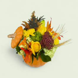 Autumn floral arrangement in a pumpkin container with yellow roses and mums