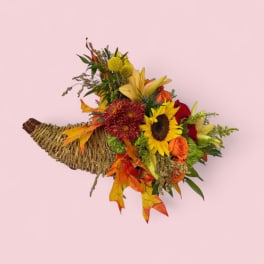 Autumn bouquet in a woven cornucopia basket with sunflowers and roses