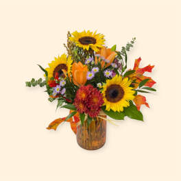 Autumn bouquet with sunflowers, orange lilies, and a glass vase