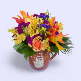 Autumn bouquet of mixed flowers in a ceramic mug vase