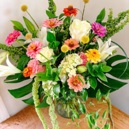 Mixed bouquet of roses, lilies, and zinnias in a glass vase