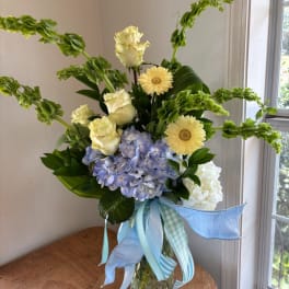 Bouquet of pale roses, blue hydrangea, and yellow daisies with ribbon