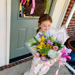 Girl holding a colorful bouquet of yellow, pink, white, and purple flowers