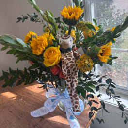 Bouquet of yellow flowers with a plush giraffe in a glass vase