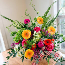 Bright mixed bouquet with gerbera daisies and roses in a ribboned vase