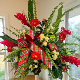 Red gerbera daisies and yellow spray roses with plaid ribbon in a vase