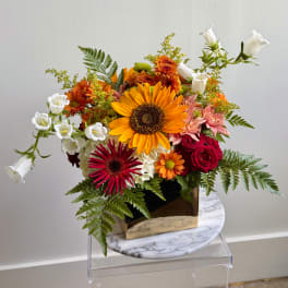 Mixed bouquet with a sunflower, roses, and white bellflowers in a gold vase