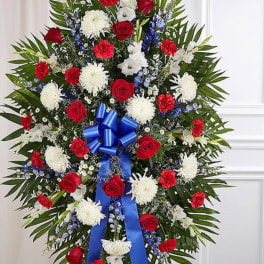 Standing floral spray with red, white, and blue flowers and a blue ribbon bow