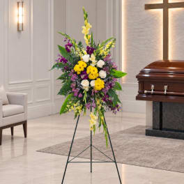Standing floral spray with yellow, white, and purple flowers on an easel