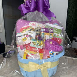 Gift basket with toys and candy wrapped in clear cellophane and a purple bow