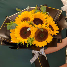 Bouquet of sunflowers wrapped in black paper with a white ribbon
