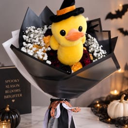 Bouquet with a plush yellow duck in a witch hat surrounded by flowers
