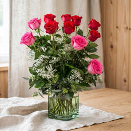 Pink and red roses arranged in a clear glass vase