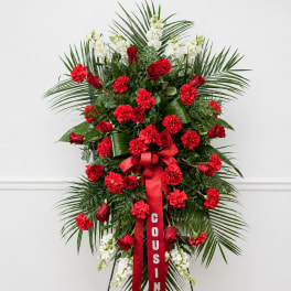 Standing red and white floral spray on an easel with a ribbon