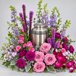 Pink roses and purple flowers arranged around a silver urn