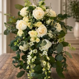Cream rose bouquet with cascading greenery on a wooden table
