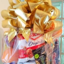 Gift basket wrapped in clear cellophane with a large gold bow