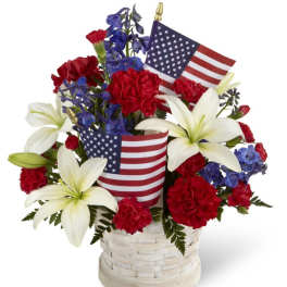 Red carnations and white lilies in a basket with small American flags