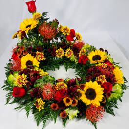 Circular floral wreath with sunflowers, red roses, and orange blooms