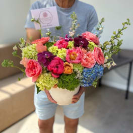 Colorful mixed bouquet in a white vase held by a person