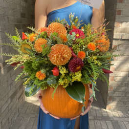 Orange and red floral arrangement in a pumpkin container