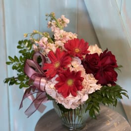Bouquet of red roses and gerbera daisies in a glass vase