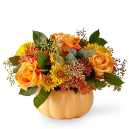 Orange roses and yellow mums in a pumpkin-shaped container