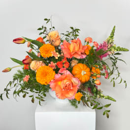 Bright mixed floral arrangement in a white vase with orange and pink blooms