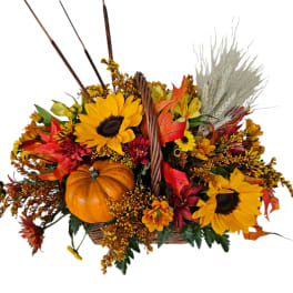 Autumn basket arrangement with sunflowers, a pumpkin, and dried grasses