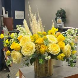 Yellow and white floral arrangement in a gold vase