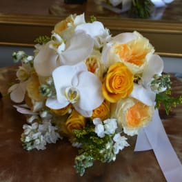 Bouquet of white orchids and yellow roses with a white ribbon