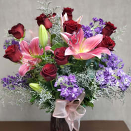 Bouquet of red roses and pink lilies in a vase with a ribbon