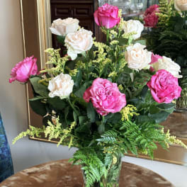 Pink and white roses arranged in a clear glass vase