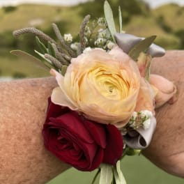 Two rose wrist corsages with ribbon and small white filler flowers