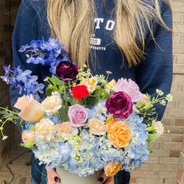 Mixed bouquet in a white vase with blue hydrangeas and roses