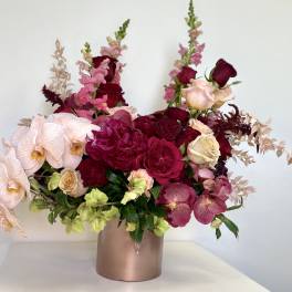 Pink and burgundy floral arrangement in a metallic vase