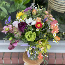 Mixed bouquet with roses, daisies, and orchids in a glass vase