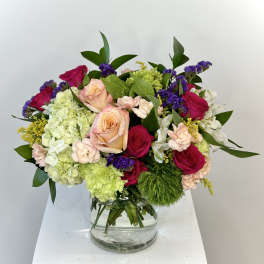 Mixed bouquet of roses, hydrangeas, and carnations in a glass vase
