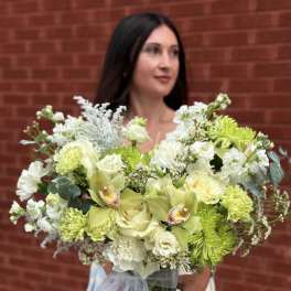 Large bouquet of pale green and white flowers in a glass vase