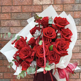 Bouquet of red roses wrapped in white paper with ribbon