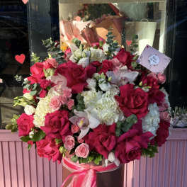 Large bouquet of pink and white roses with orchids in a hatbox
