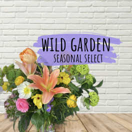 Mixed bouquet with lilies, poppies, and roses in a glass vase