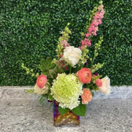 Mixed bouquet in a square glass vase with pink, white, and green blooms